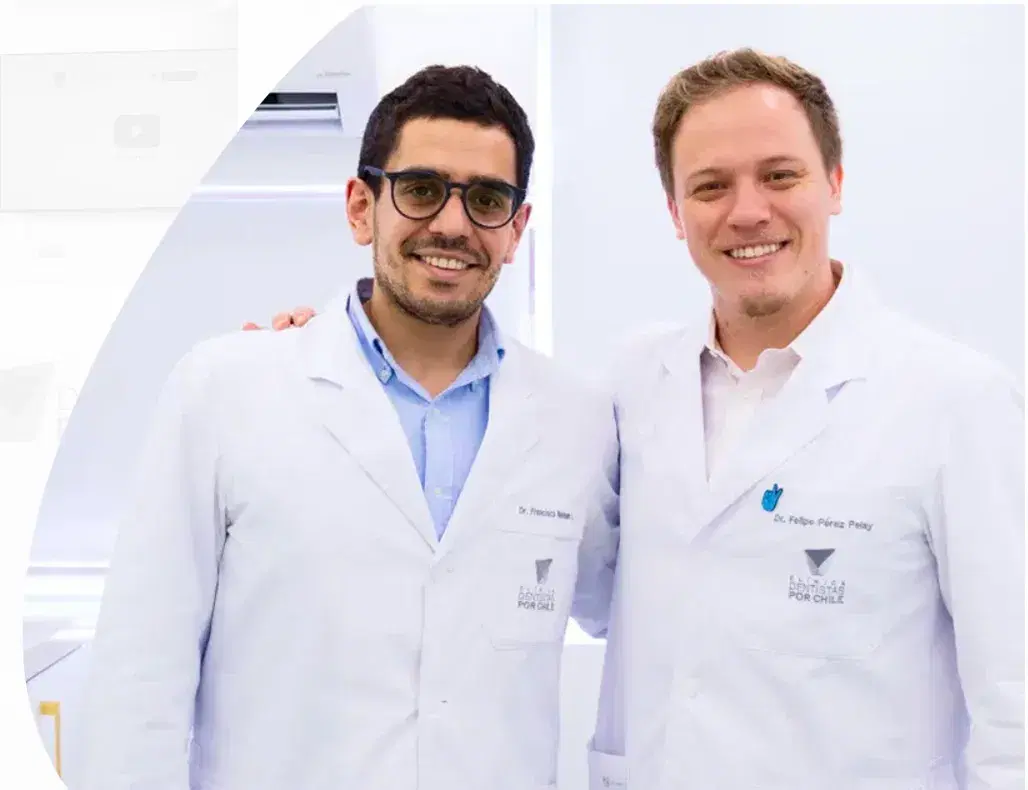 Dos cirujanos dentistas de Dentistas por Chile, con delantal blanco, sonriendo en la clínica